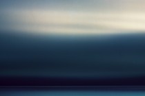 A long exposure of a passing storm over the horizon of the Pacific Ocean off the Oregon coast.  The long exposure renders the clouds as an abstract blur of motion and color and the setting sun highlights the higher clouds with a warm glow while the lower clouds are dark and brooding.