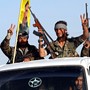 Three fighters of the Syrian Democratic Forces make the V-sign as their convoy passes 
