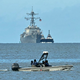 A speedboat of the Trinidad and Tobago Coast Guard patrols as the USS Gravely warship is seen at a distance from Port of Spain