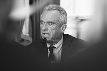 a black and white photograph of Robert F. Kennedy Jr. speaking into a microphone