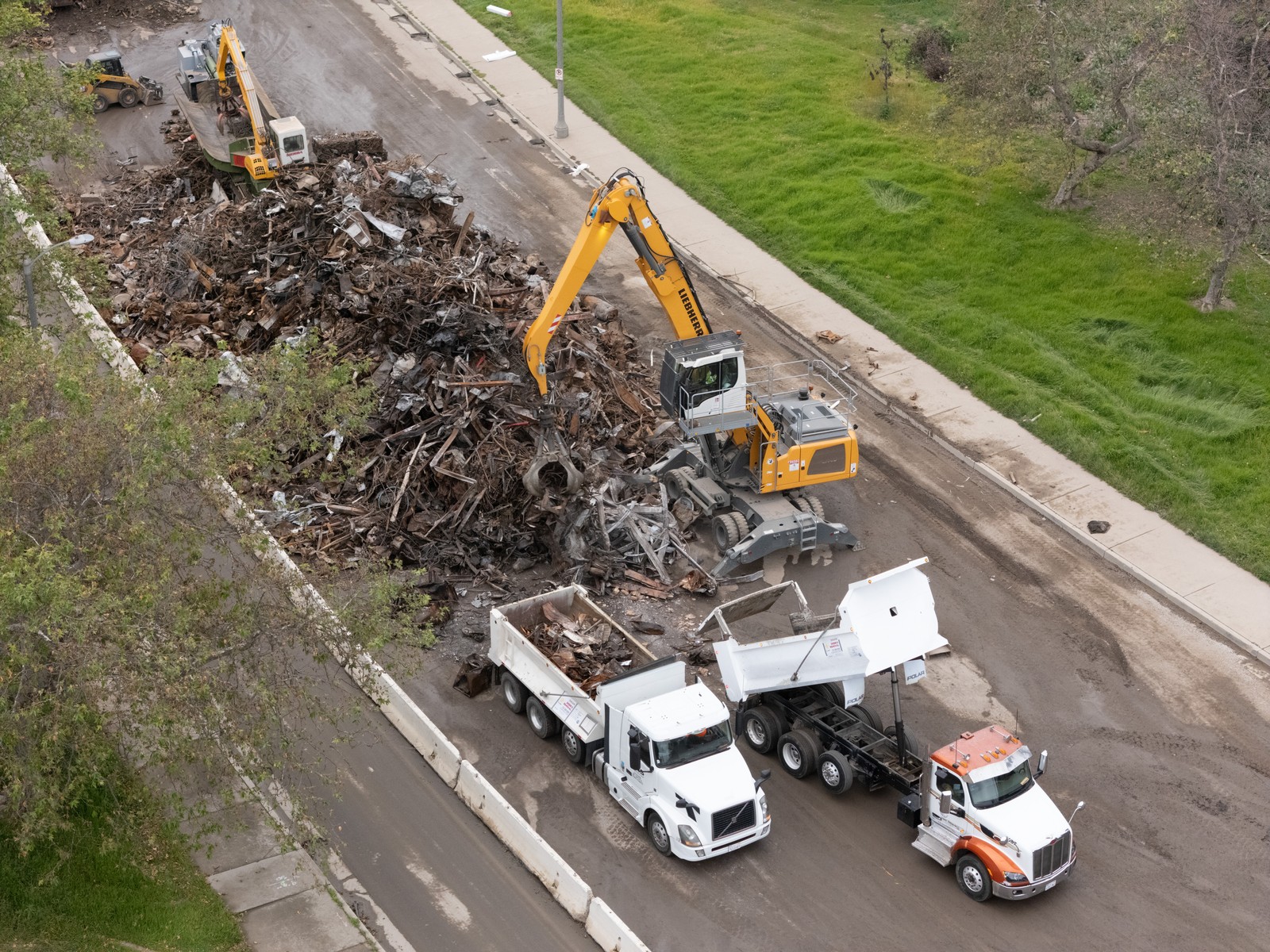 Construction equipment is used to crush and break down debris from destroyed houses.