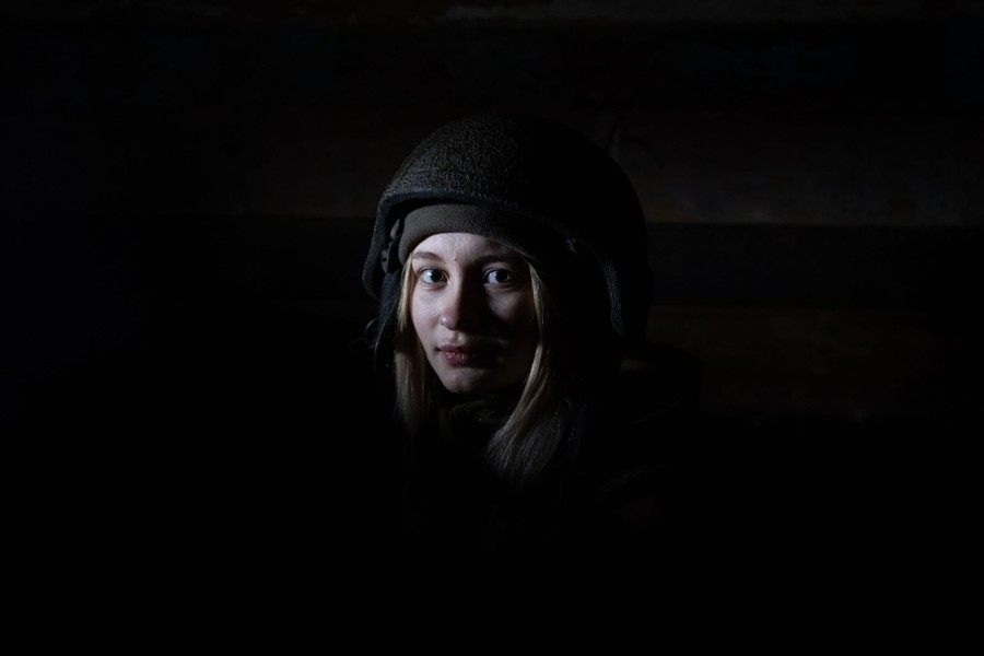 The face of a young soldier is seen in a dark setting.