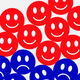 An illustration of red smiley faces on top of blue frowny faces