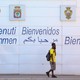 A person walks in front of a wall that says "Welcome" in different languages.