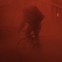 A person riding a bicycle in a red fog 