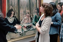 A group of bystanders look at a painting.