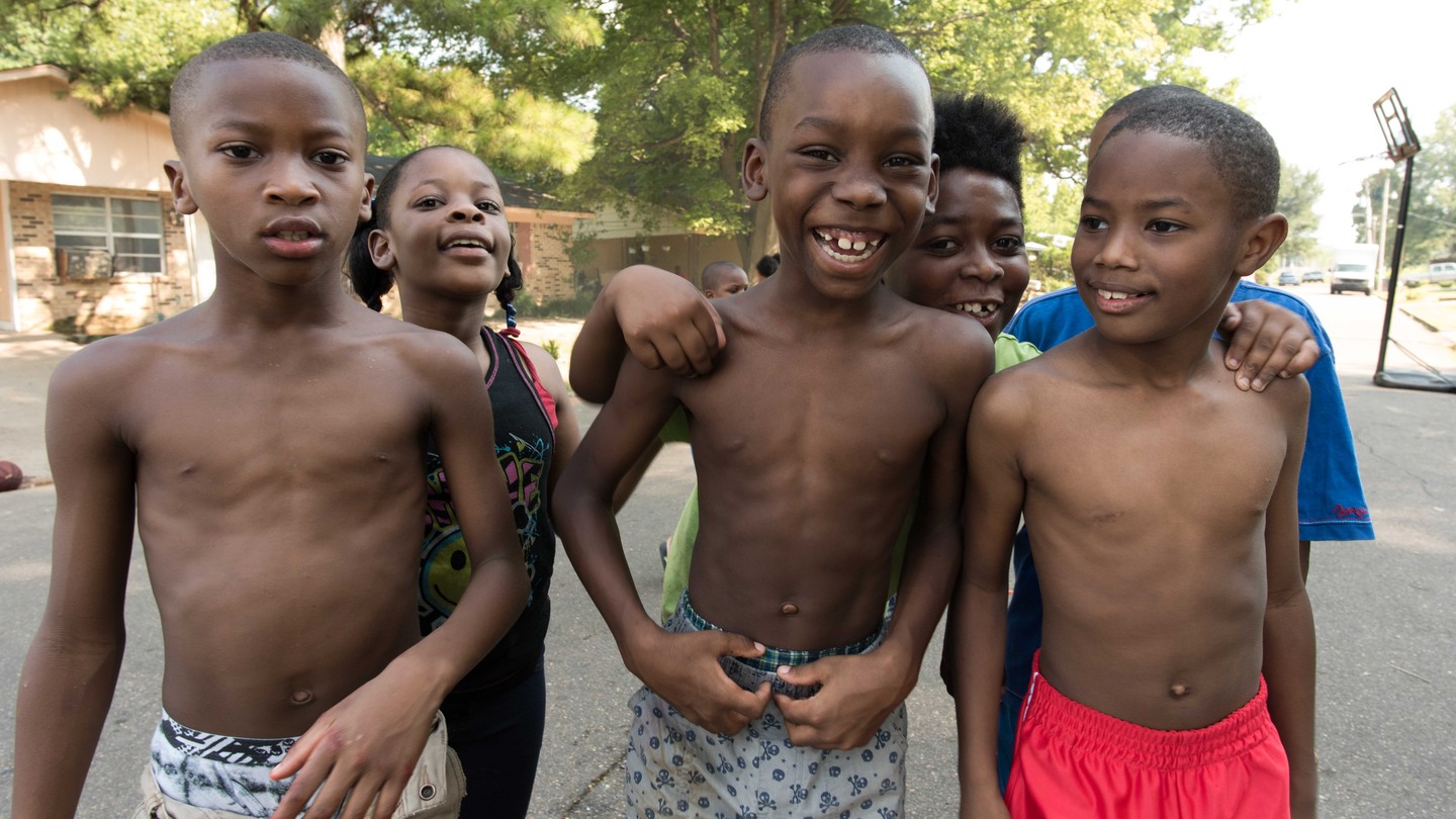 A group of young Black children smile for the camera.