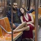 Marnie wears a red dress and leans on Charlie's shoulder in a subway