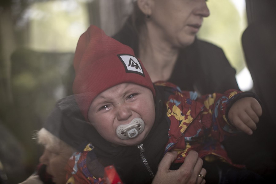 A woman holds a crying child inside a bus.
