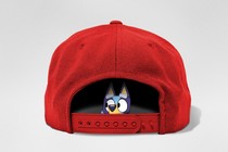 Cartoon dog is looking out from inside of a red baseball cap looking worried on an empty background