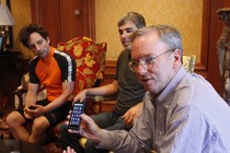 One man holds up an Android phone while two others look on.