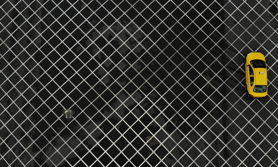 A single taxi drives on an otherwise empty street.