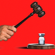 A photo illustration of a hand wielding a gavel and smashing a vaccine vial, all on a red background