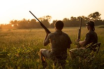 A photograph of two people hunting with rifles