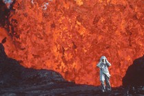 Katia Kraft wearing an aluminized suit standing near a lava burst at Krafla Voclano, Iceland