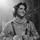Timothée Chalamet wearing a thick knit sweater holding backpack straps and wearing over-ear headphones, in black and white