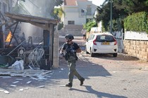 A member of the Israeli forces runs past a fire in Ashkelon following a rocket attack from the Gaza Strip.