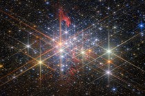 Hundreds of bright and differently colored stars, seen in a cluster, with most stars displaying six long diffraction spikes, artifacts of the telescope's structure