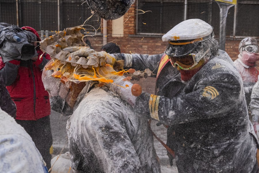 People enjoy a food fight of sorts, dousing one another with flour and smashing open cartons of eggs on one another's heads.