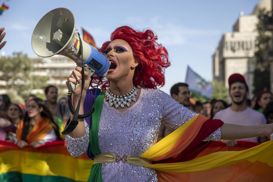 A person speaks into a bullhorn while walking among many others during a gay-pride parade.