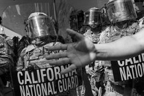 A photograph of the California National Guard, with a hand reaching in front of the camera lens