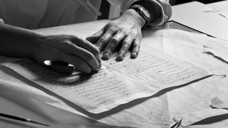 Black-and-white image of a pair of hands on top of a manuscript