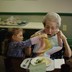 A toddler feeding an elderly woman from a fork.