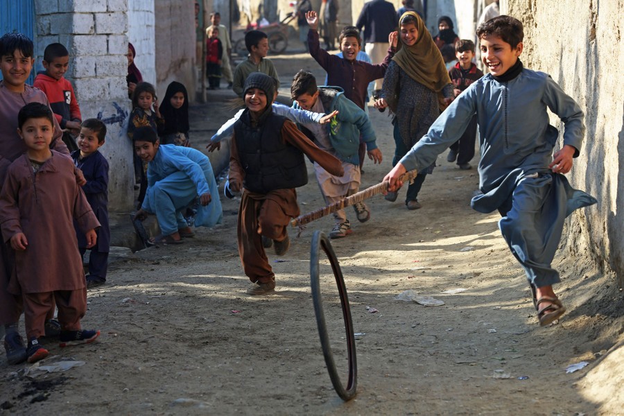 Children play with a tire along a street in Afghanistan.