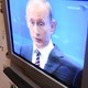 Photo of an elderly woman feeding a baby with Vladimir Putin on T.V.