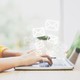 woman in yellow sweater using laptop computer with white email envelope icons hovering above the keyboard