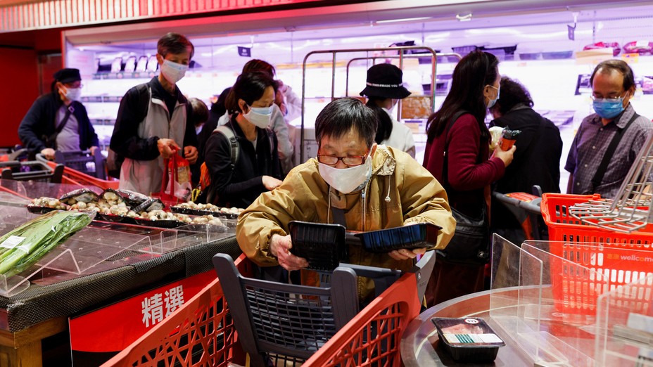 A customer wearing a mask buys fresh meat at a supermarket.