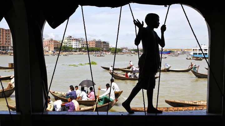 A boy walks along the side of a passenger ferry docked near Dhaka, Bangladesh.