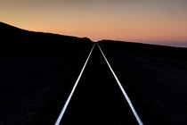 A pair of railroad tracks extend into the sunset