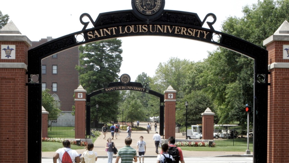 Students walk under an arch reading "Saint Louis University"