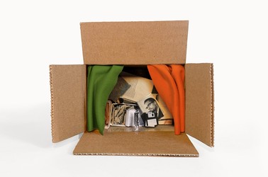 A cardboard box contains a collection of artifacts, including a photo of Malcolm X