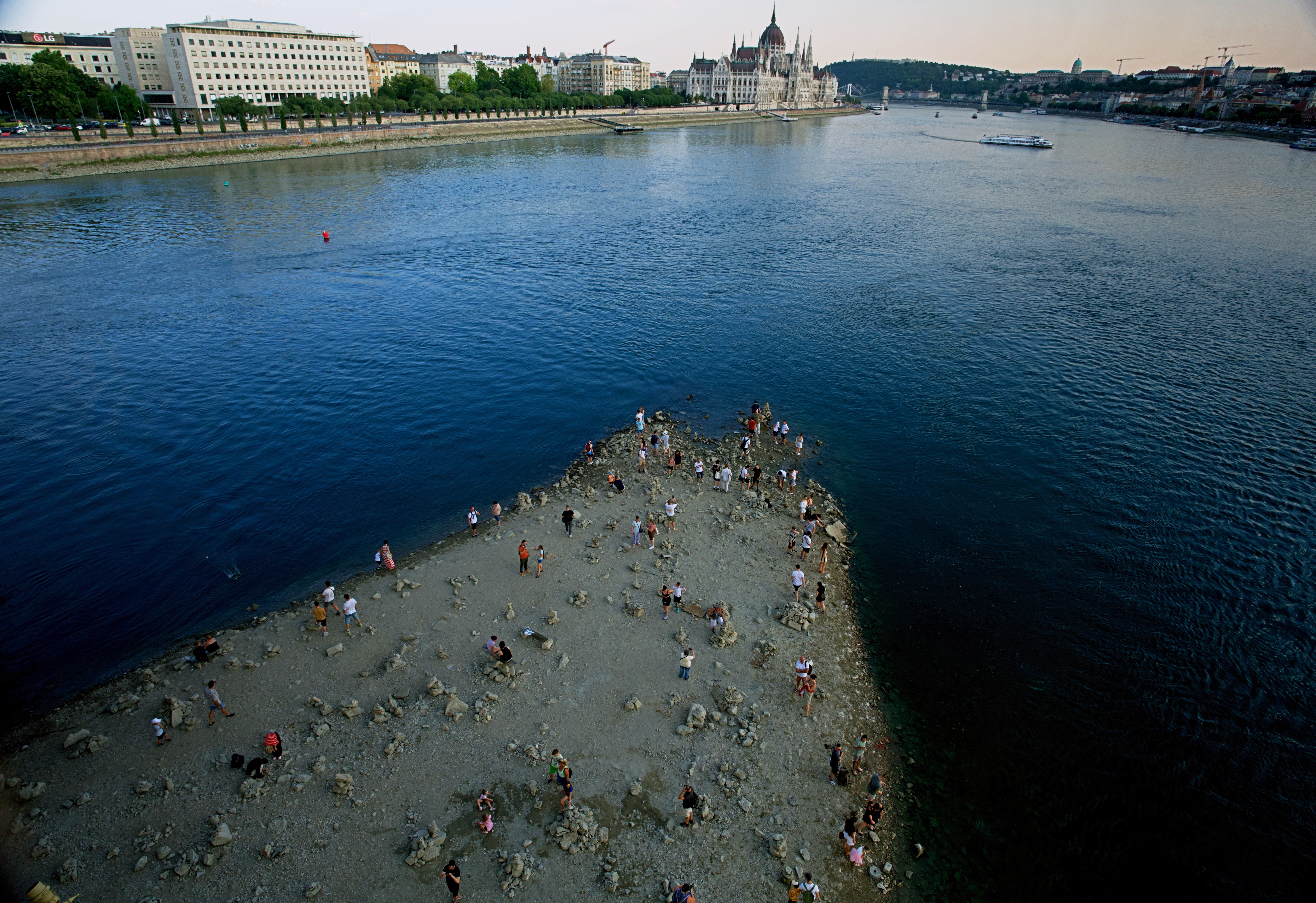 People walk on a sandbar in the middle of the Danube River in Budapest.
