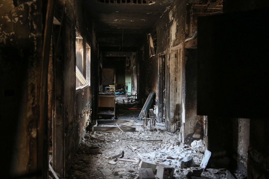 A scorched and rubble-strewn hallway in a war-damaged hospital