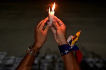 A woman holds a candle at a vigil in honor of Venezuelans detained during protests challenging the presidential election results, Caracas, December 17.