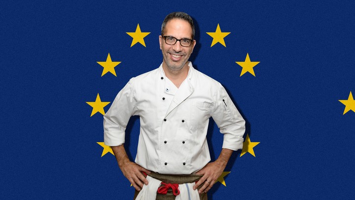 Yotam Ottolenghi stands in front of a European Union flag.