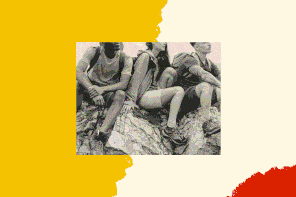 A black-and-white photo shows three hikers sitting on a mountain with backpacks on. They are looking out to the horizon.