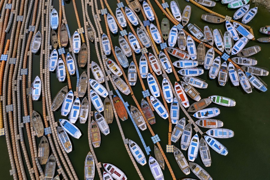 Dozens of boats are tied up in a river in an aerial view.