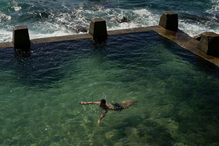 A person swims in a shoreside pool.