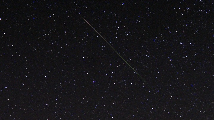 A thin diagonal line of light is shown against a starry sky.
