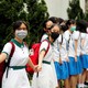 Secondary-school students wearing face masks hold hands, forming a long human chain.