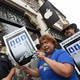 Workers holding signs and protesting in front of an Apple store