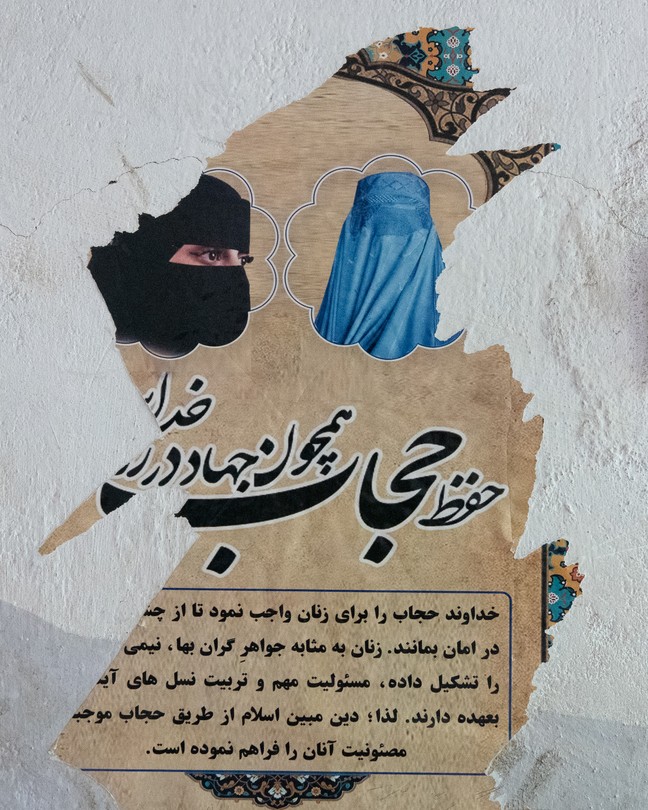 A torn poster on a wall featuring a woman in a niqab and a woman in a burqa.