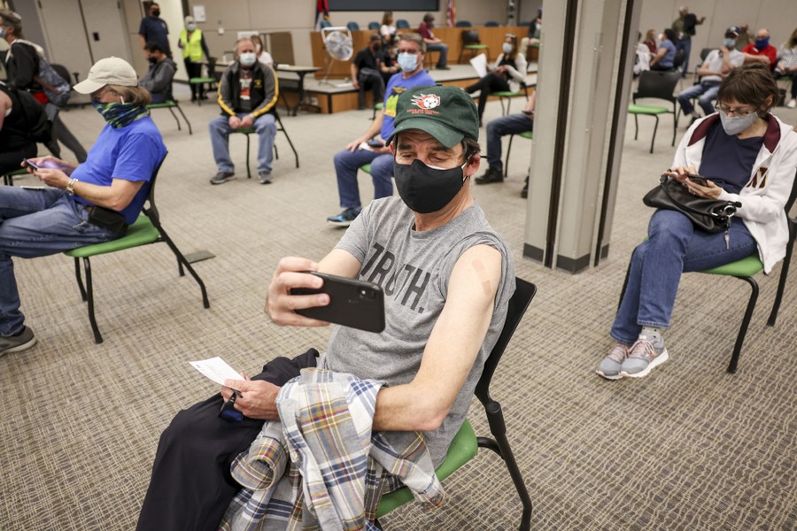 A man takes a selfie while seated in a waiting area.