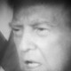 Pixelated black-and-white photograph of Donald Trump with an American flag behind him