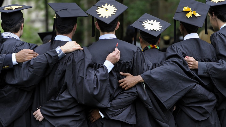 College graduates are shown from behind, with arms around each other