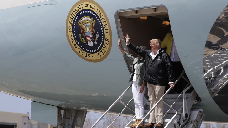 Donald and Melania Trump wave from the stairs of a plane.